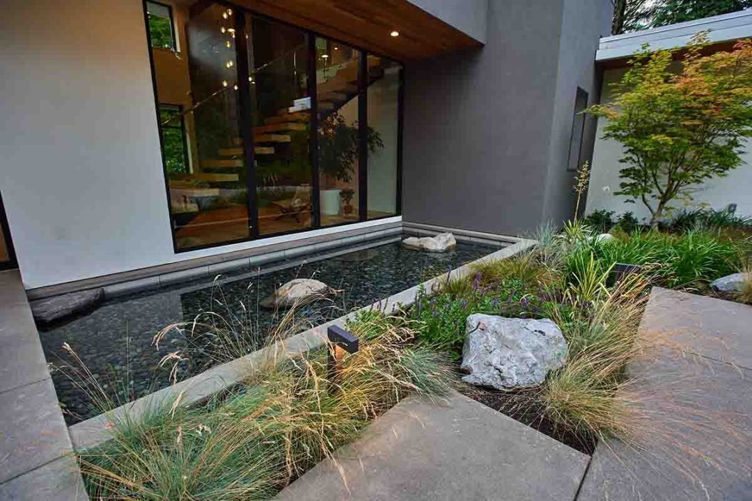 Modern rectangular pond water feature with natural rocks, against a house - 7 Dees Landscaping