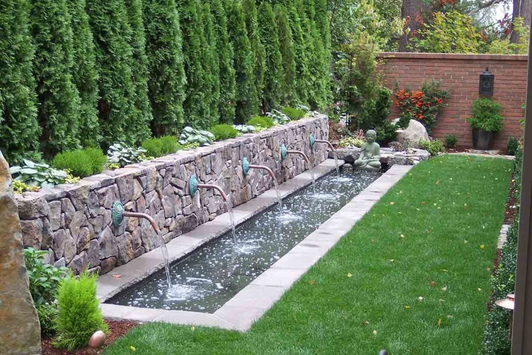 In-ground long rectangular water feature with 5 spigots in a backyard - 7 Dees Landscaping