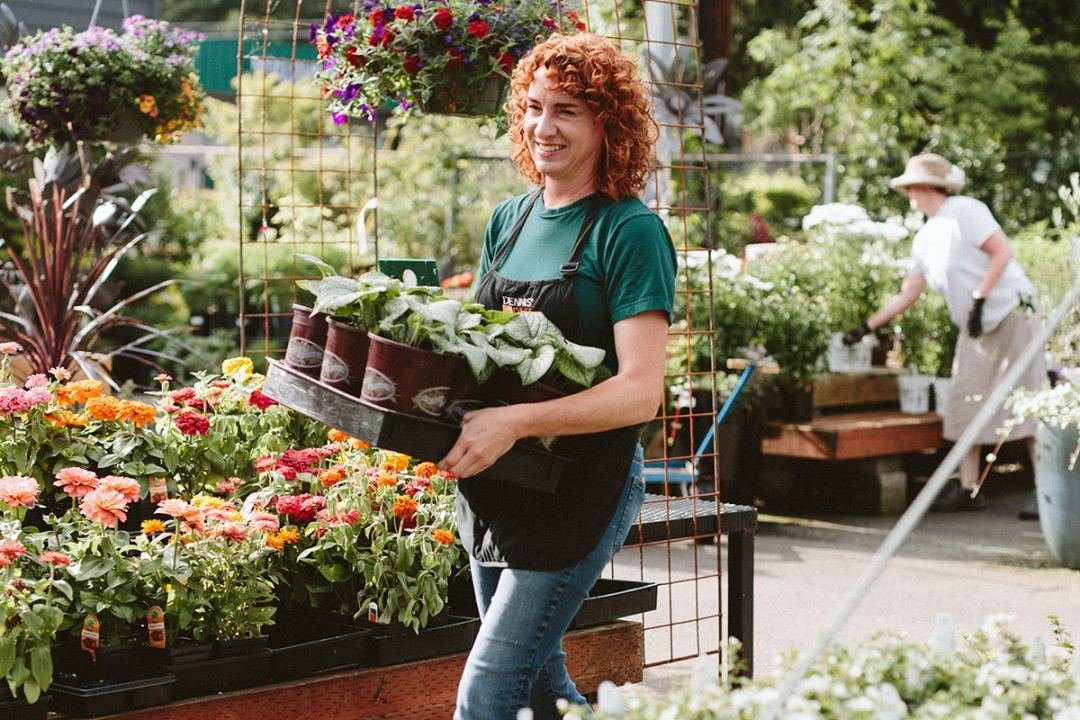 Garden center worker holding plants in pots