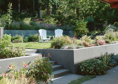 Backyard design with poured steps, retaining walls, and adirondack chairs by Dennis' 7 Dees Landscaping