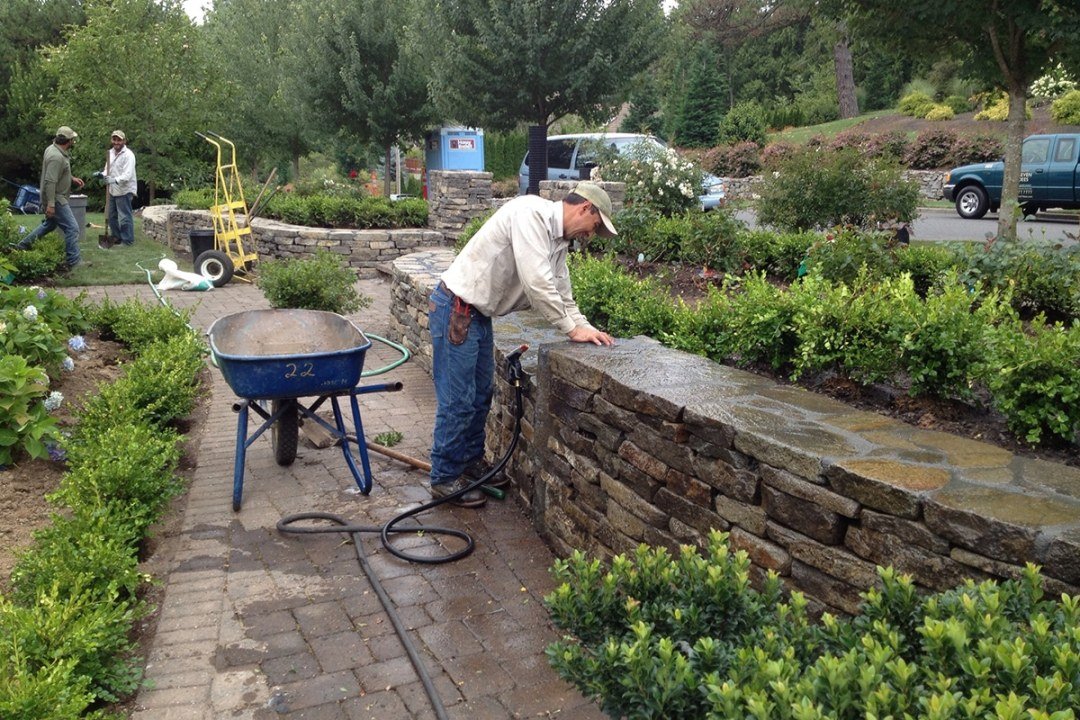 Crews install plants in a retaining wall planter bed as a landscape is built - 7 Dees Landscaping