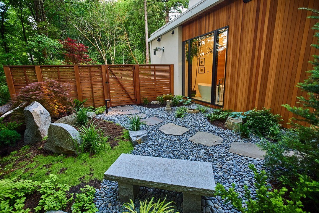 bench and stone pathway with shade plants and wood fence