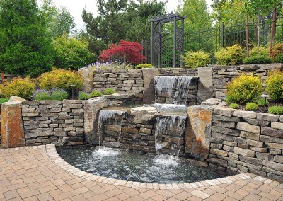 Intricate waterfall water feature and hardscape design by Dennis' 7 Dees Landscaping