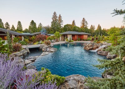 Large natural pool with various water features by Dennis' 7 Dees Landscaping