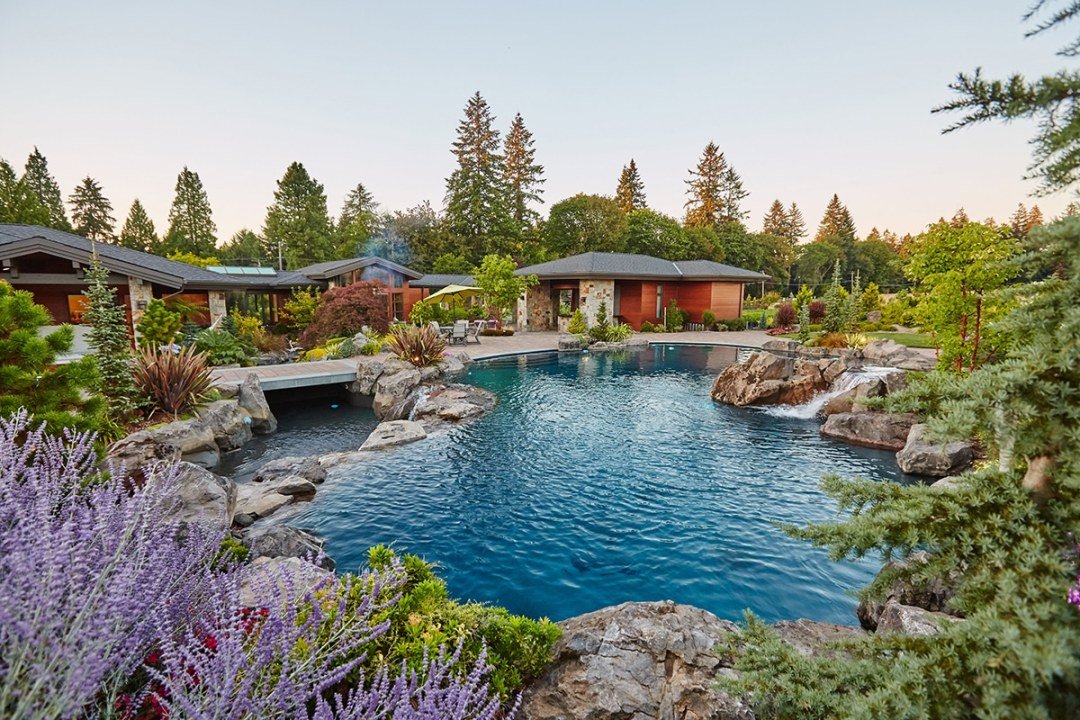 Large natural pool with various water features by Dennis' 7 Dees Landscaping