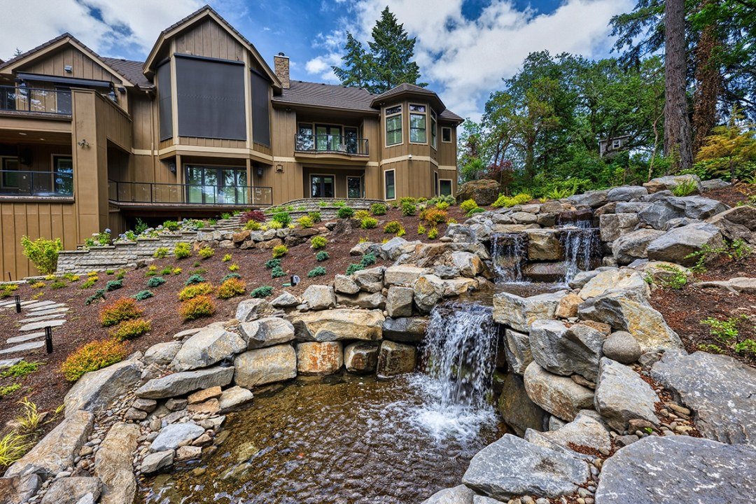 Natural stone waterfall water feature designed on a sloped landscape by Dennis' 7 Dees