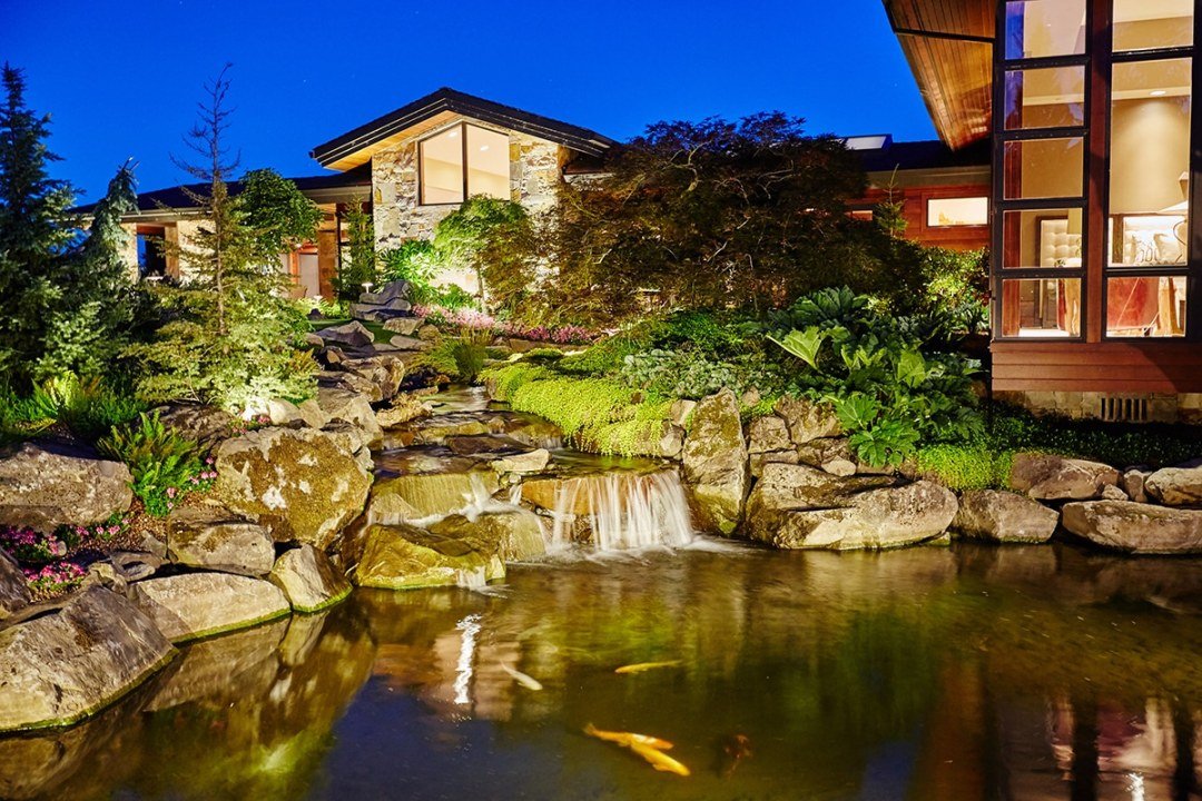Natural stone trickling waterfall water feature and koi pond by Dennis' 7 Dees Landscaping